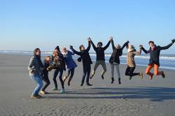 Gruppe junger Leute springt am Meer nach oben